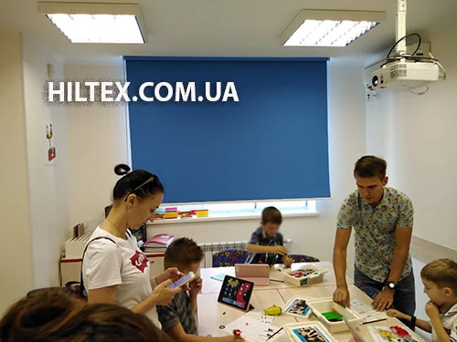 Тканева ролета на вікні синього кольору в дитячому закладі